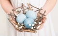 CildÃ¢â¬â¢s hands holding easter eggs in nest made of sticks Royalty Free Stock Photo